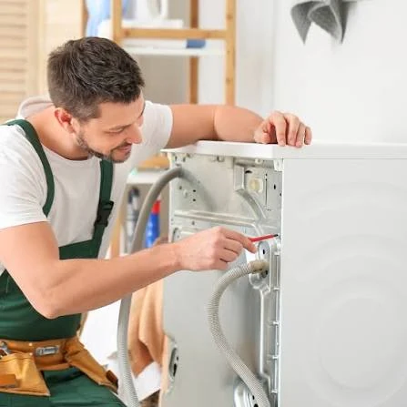 Technician inspecting the rear connections of a laundry appliance